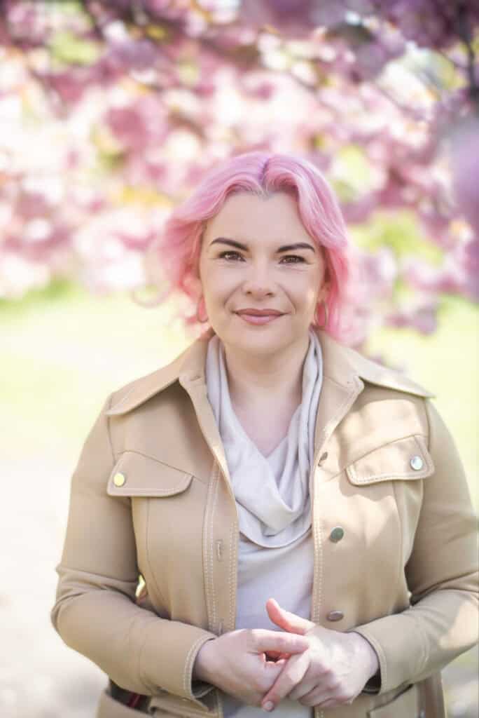 Dog Separation Anxiety Trainer Petrina Firth - picture of woman with pink hair and a floral background.